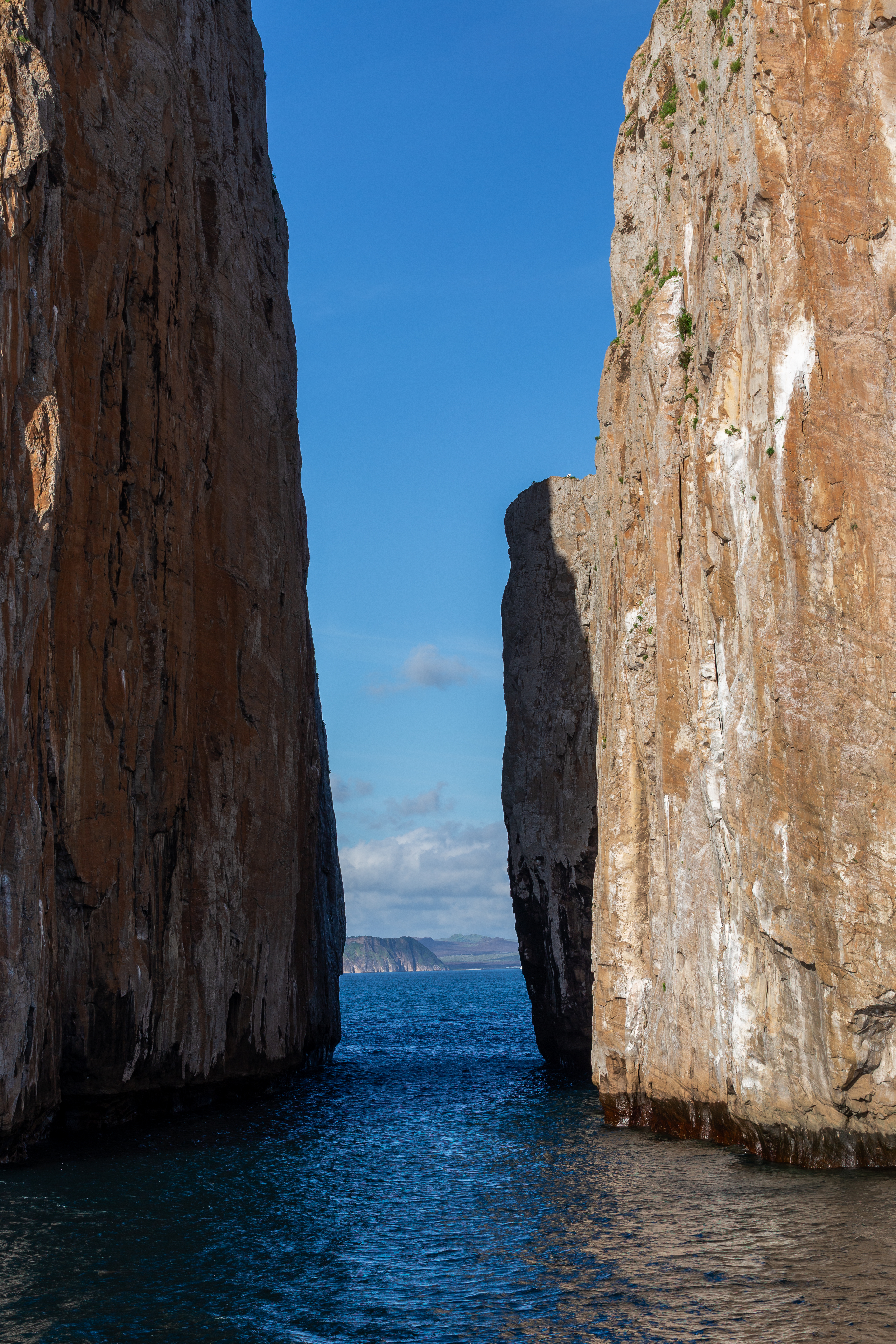 Narrow channel of blue water between two tall orange rock walls